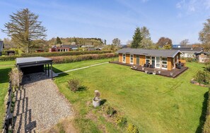 Ein eingeschossiges Holzhaus mit überdachter Außenveranda und gepflegtem Rasen.