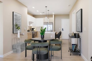 A modern kitchen with white cabinets, a central island, and pendant lighting. - Upscale Condo in Downtown with Pool, Balcony, Gym + Garage (Nashville)
