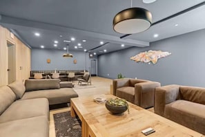 A modern lounge area with sofas, a wooden coffee table, and pendant lighting. - Upscale Condo in Downtown with Pool, Balcony, Gym + Garage (Nashville)