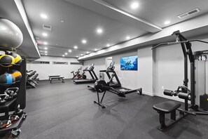 Ein Fitnessraum mit Cardiogeräten, Krafttrainingsgeräten und einer Bank.