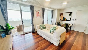 Een woonkamer met een bank, een eettafel en een plafondventilator.