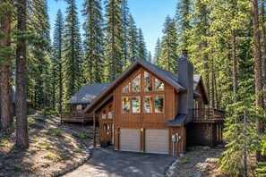 A cabin with a garage, surrounded by tall pine trees. - Hawk’s Ridge: Forest Cabin Mins to Lake - AC, BBQ, EV, workspace, backyard (Tahoe Vista)