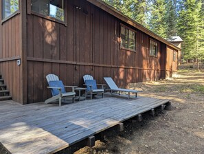 A wooden cabin with a deck, two lounge chairs, and a table. - Hawk’s Ridge: Forest Cabin Mins to Lake - AC, BBQ, EV, workspace, backyard (Tahoe Vista)