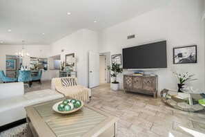 A modern living room with a sofa, a dining area, and a television on the wall. - Beautiful modern 2-bedroom villa with gorgeous views in Ironwood CC Palm Desert (Palm Desert)