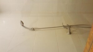 Une douche équipée d’un pommeau de douche à main et d’un flexible.