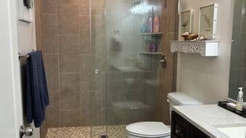 A modern bathroom with a glass-enclosed shower, a toilet, and a vanity with a sink.