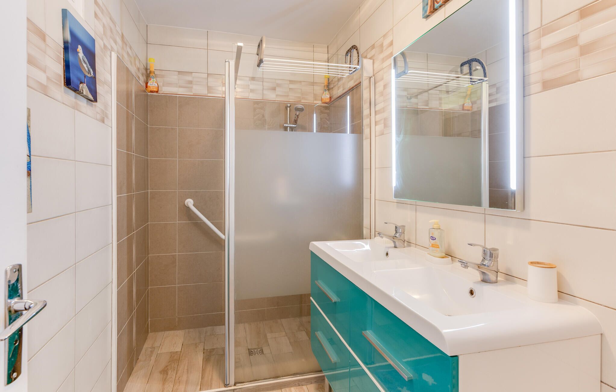 A bathroom with a glass shower enclosure, a white sink with two faucets, and a mirror above the sink.