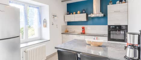 Eine moderne Küche mit eingebautem Herd, einer Kaffeemaschine und einem Kühlschrank.