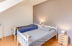 A bedroom with two beds, a nightstand, a dresser, and a wooden floor. - Amazing home in Ploubazlanec with WiFi (Ploubazlanec)