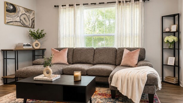 A modern living room with a sectional sofa, a coffee table, and a bookshelf. - Luxury 1BR Condo 8 min Walk to Mercedes-Benz (Atlanta)