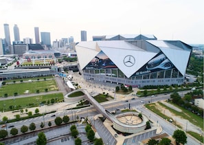A modern, angular building with a prominent Mercedes-Benz logo, surrounded by a well-maintained urban area with roads and greenery.