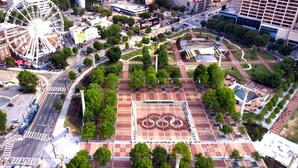 An aerial view of a city square with a large Ferris wheel, a plaza with trees, and a building with a sign that reads 'MOVIE CENTER'. - Luxury 1BR Condo 8 min Walk to Mercedes-Benz (Atlanta)