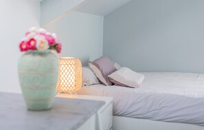 Ein Schlafzimmer mit einem Bett, einem Nachttisch, einer Lampe und einer Vase mit Blumen.