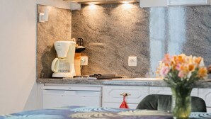 Een moderne keuken met een koffiezetapparaat, een spoelbak en een vaas met bloemen op het aanrecht.