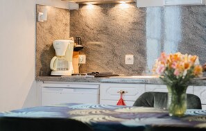 Eine moderne Küche mit Kaffeemaschine, Spüle und einer Vase mit Blumen auf der Arbeitsfläche.