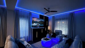Un saló modern amb televisió de pantalla plana, ventilador de sostre i il·luminació ambiental.