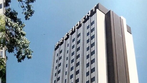 Un edificio alto y moderno con un letrero grande que dice 'PRESIDENT' en la parte superior.
