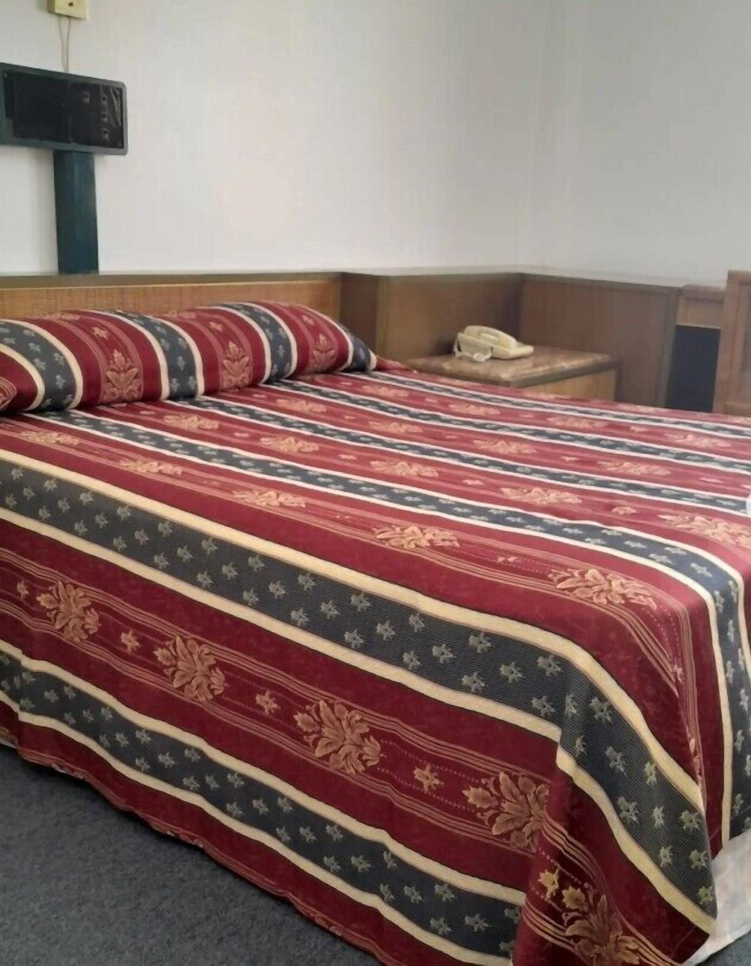 Una habitación de hotel estándar con cama, mesita de noche y teléfono.