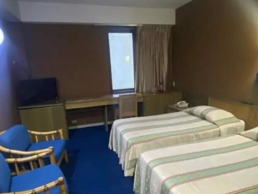 A hotel room with a single bed, a desk, a chair, and a television.
