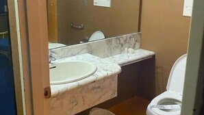 Un baño con lavamanos de mármol, inodoro y cubo de basura.