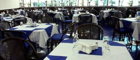 A banquet hall with tables set for dining, chairs, and a view of the outdoors through large windows.
