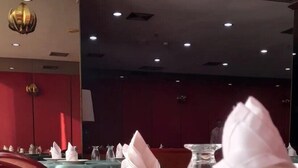 Un salón de restaurante con mesas dispuestas para comer, incluyendo platos, cubiertos y servilletas dobladas.