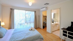 Hotellihuone, jossa on sänky, ikkuna verhoilla, yöpöytälamppu, kylpyhuone, jossa on pesuallas ja peili, sekä ilmastointilaite.