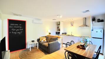 A compact living space with a kitchenette, a dining area, and a seating area with a sofa and a small table.