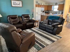 Ein Wohnzimmer mit zwei Ledersofas, einem Streifen Teppich und einer Küche im Hintergrund.
