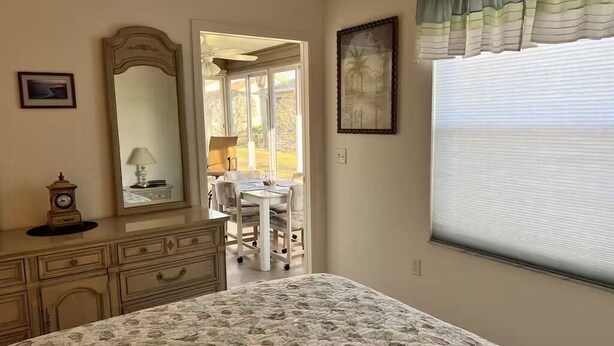 Une chambre à coucher avec un lit, une commode, un miroir et une fenêtre avec des stores.