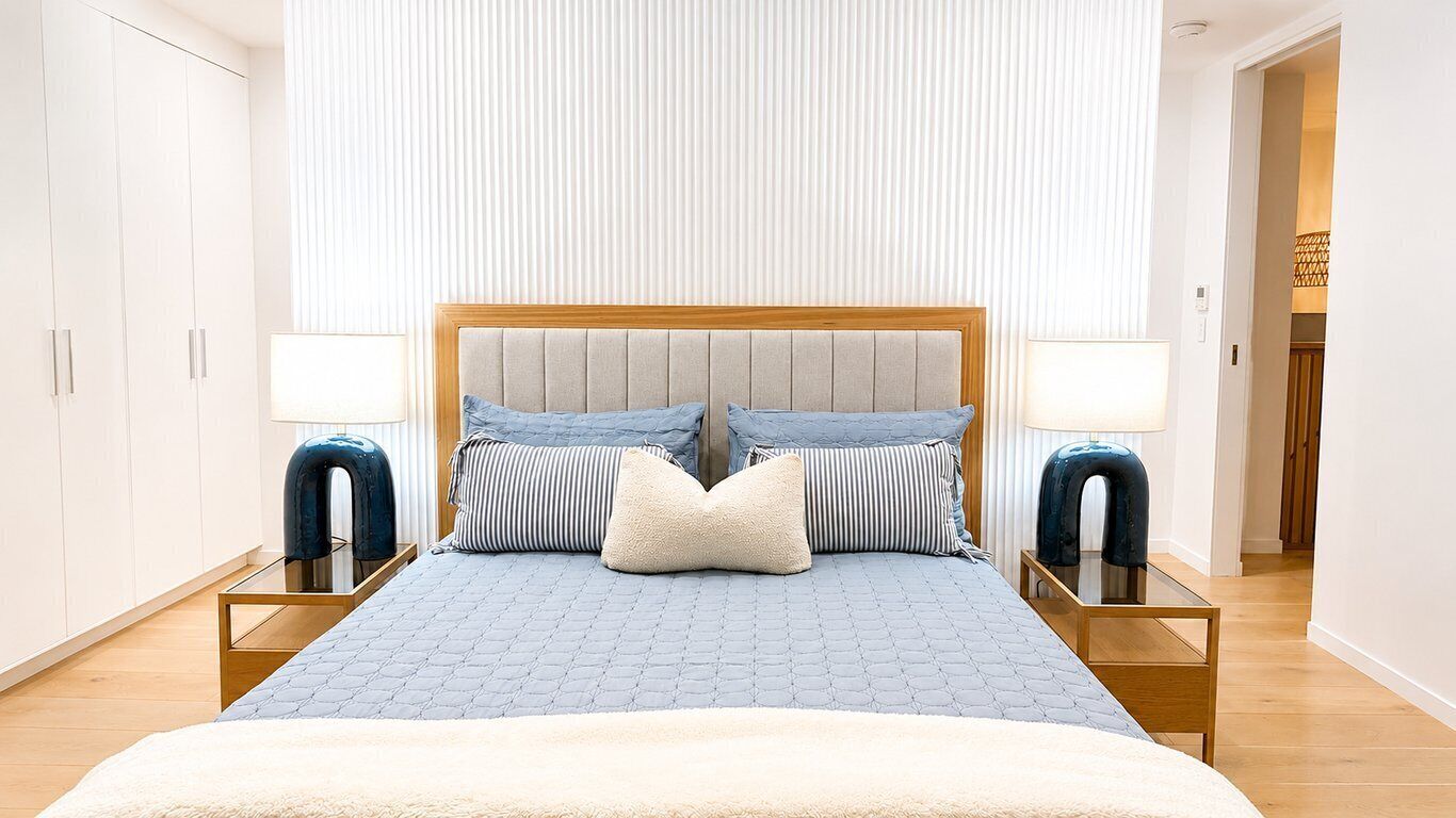 A bedroom with a large bed, two bedside tables, and a wardrobe.