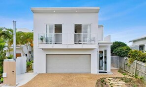 A modern two-story house with a white exterior, a garage, and a balcony.