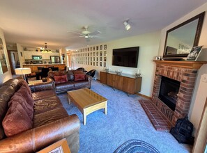 Uma sala de estar com lareira, televisão e um espaço de refeições ao fundo.