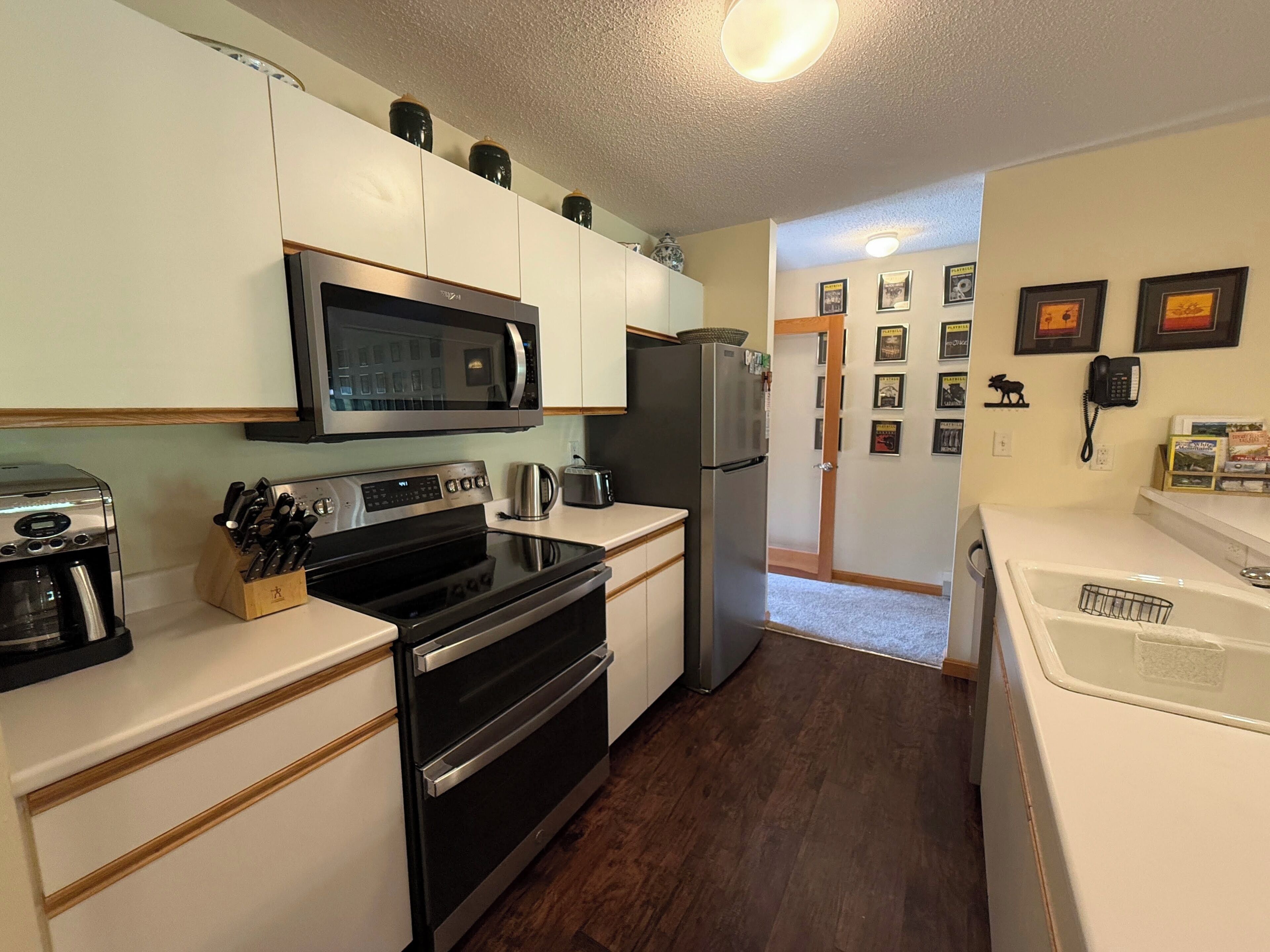 Una cocina compacta equipada con microondas, horno, refrigerador y cafetera.