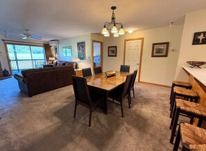 A spacious living area with a dining table, chairs, a sofa, and a ceiling fan.