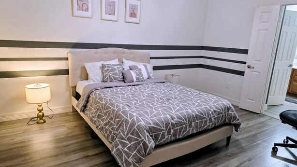 Een slaapkamer met een bed, een bedlamp en drie foto's in lijstjes aan de muur.