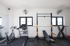 Ein Fitnessstudio mit Trainingsgeräten, darunter Laufband, Crosstrainer und eine Gewichthebezone.