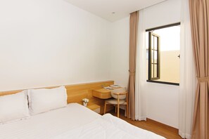 Una camera d'albergo con un letto, una scrivania, una sedia e una finestra con tende.