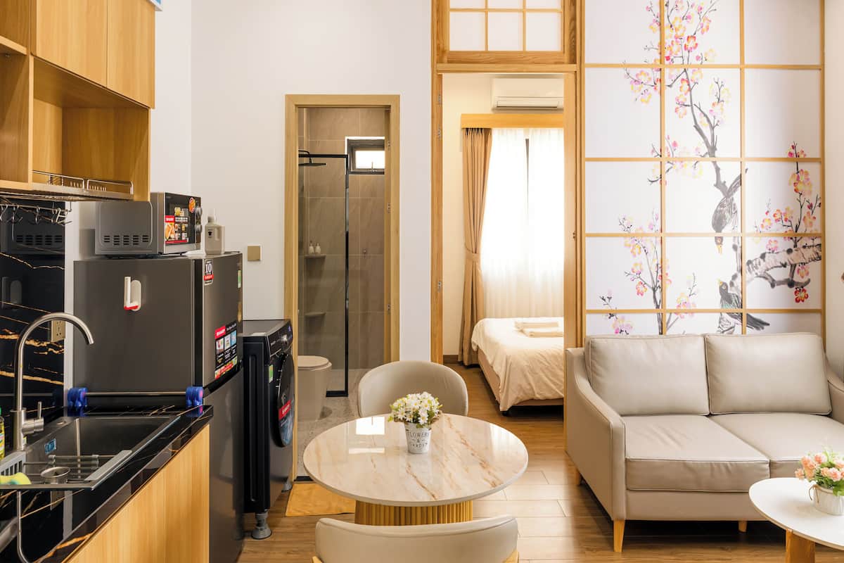 Ein kompaktes Hotelzimmer mit Küchenzeile, Essbereich, einer Couch und einer traditionellen japanischen Schiebetür.