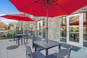 An outdoor patio with stone walls, large red umbrellas, and modern furniture. - Chic & Modern 2BR Condo (Salt Lake City)