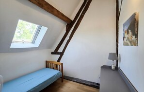 A small room with a sloped ceiling, a single bed, a window, and a painting on the wall. - Nice home in Manthelan (Manthelan)