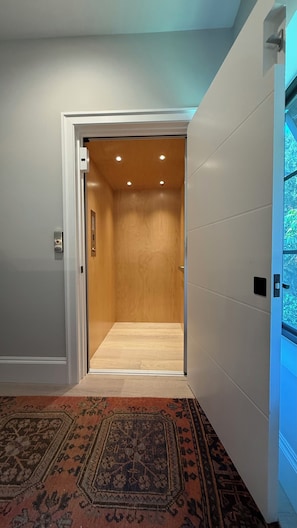 A hallway with a carpeted floor leading to an elevator. - Cozy 1-BR 1-Bath house close to Beach in Naples, FL with A/C. (Naples)