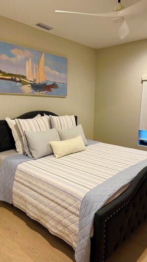 A bedroom with a bed, pillows, a painting, a ceiling fan, and a bedside table. - Private guest house near Beach Restaurants Shopping!. (Naples)