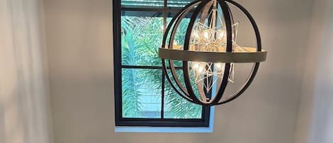 A staircase with a wooden finish and black railings, leading to a landing with a black-framed window overlooking greenery.