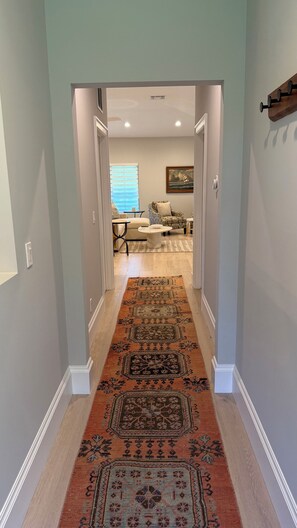 A hallway leading to a living area with a patterned rug, a sofa, and a painting on the wall. - Private guest house near Beach Restaurants Shopping!. (Naples)