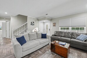 A living room with a grey sofa, a leather sofa, and a wooden coffee table. - Ocean Springs Retreat, 5 min to downtown, Sleeps 8 (Ocean Springs)