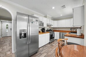 A modern kitchen with stainless steel appliances, white cabinetry, and a herringbone-patterned floor. - Ocean Springs Retreat, 5 min to downtown, Sleeps 8 (Ocean Springs)