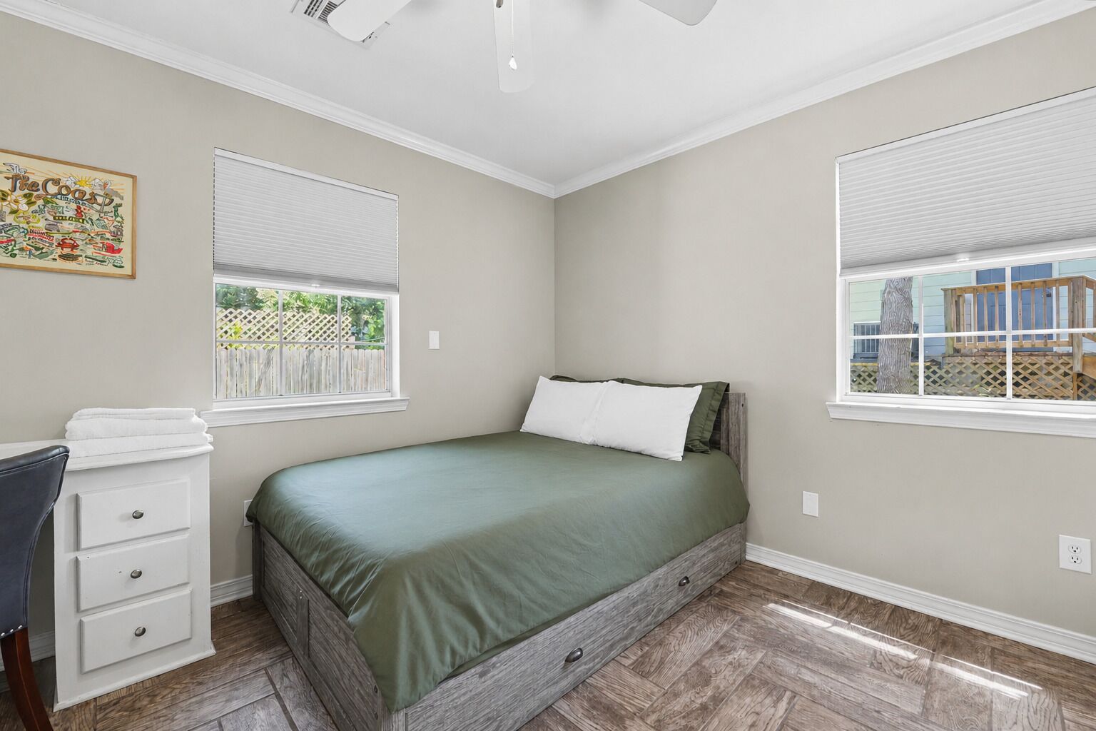 A bedroom with a bed, a dresser, and two windows.