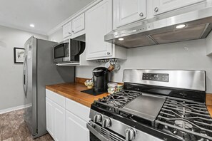 A modern kitchen with stainless steel appliances, including a refrigerator, microwave, and gas stove. - Ocean Springs Retreat, 5 min to downtown, Sleeps 8 (Ocean Springs)