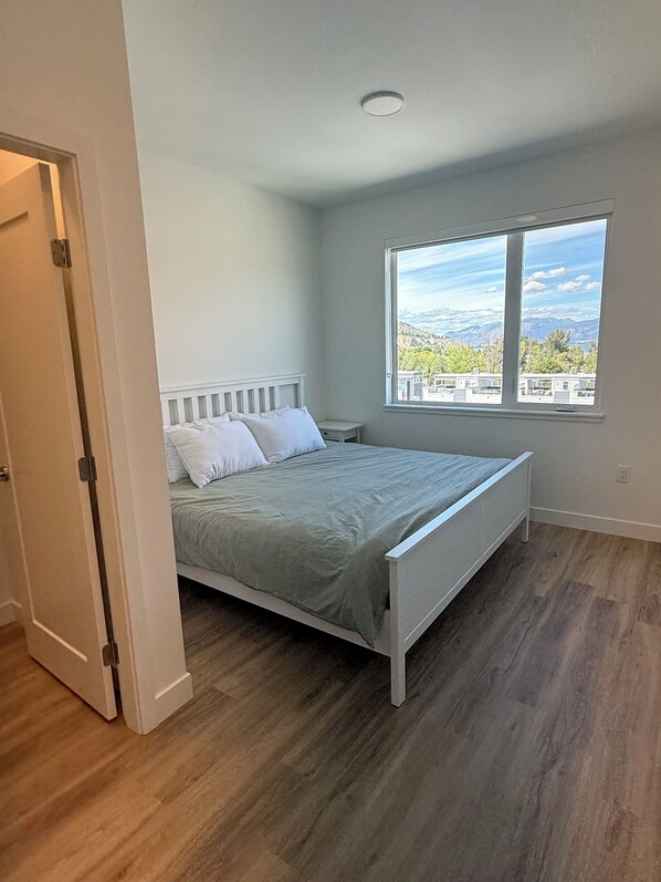 A bedroom with a bed, a window with a view, and a door.